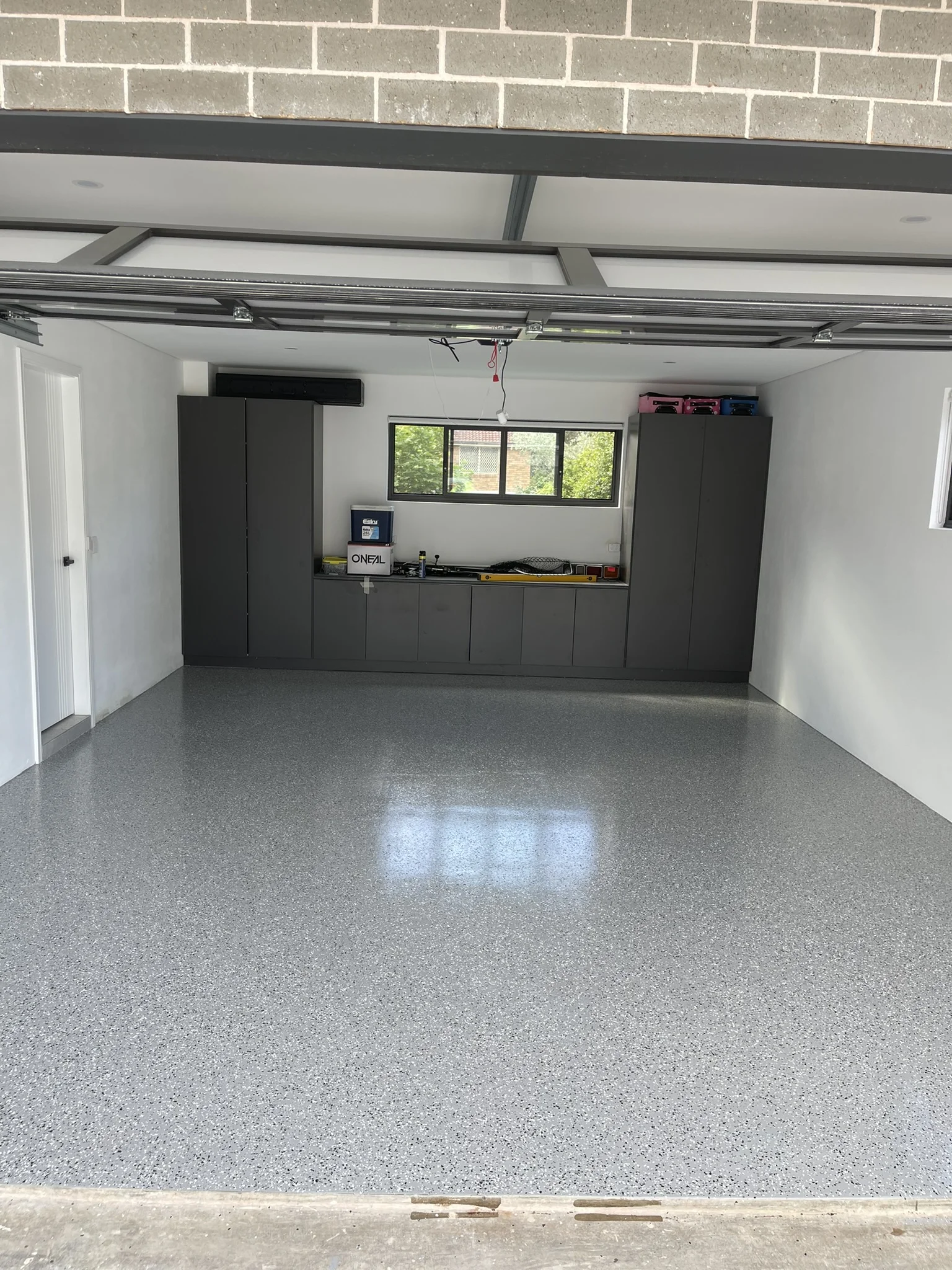 Finished flake epoxy garage floor with dark cabinetry