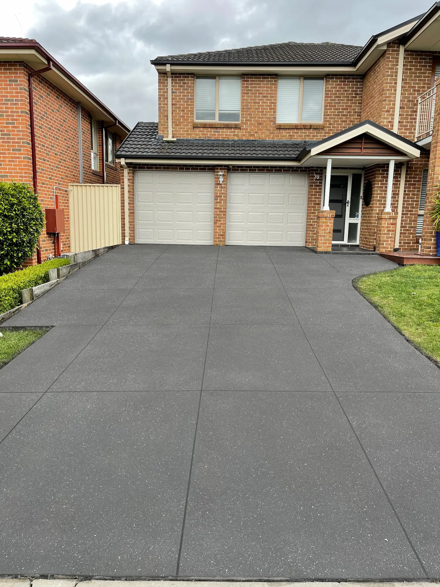 Charcoal spray-crete driveway on a two-storey brick home