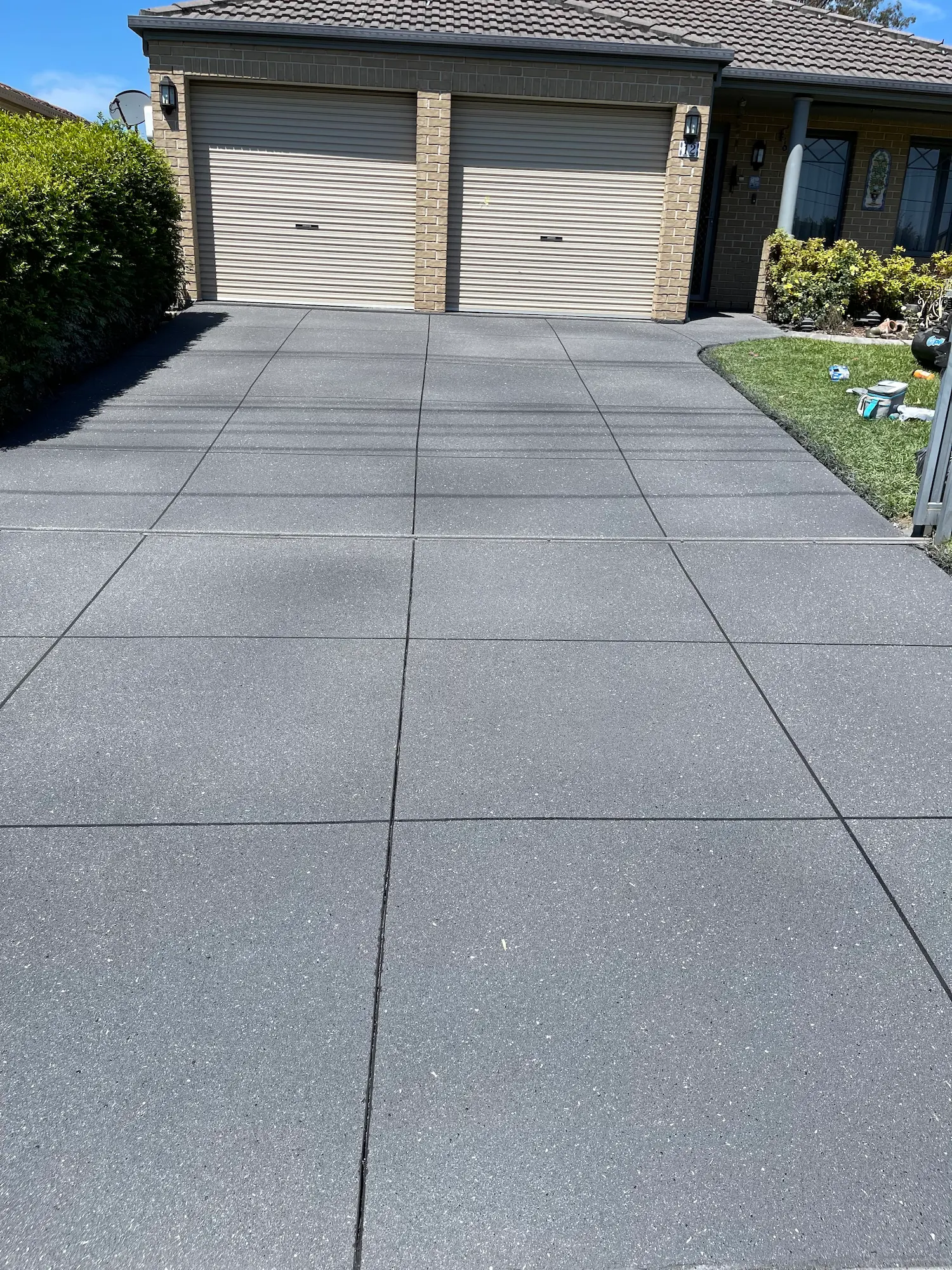 Close view of a sealed, flecked box-pattern spray-crete driveway