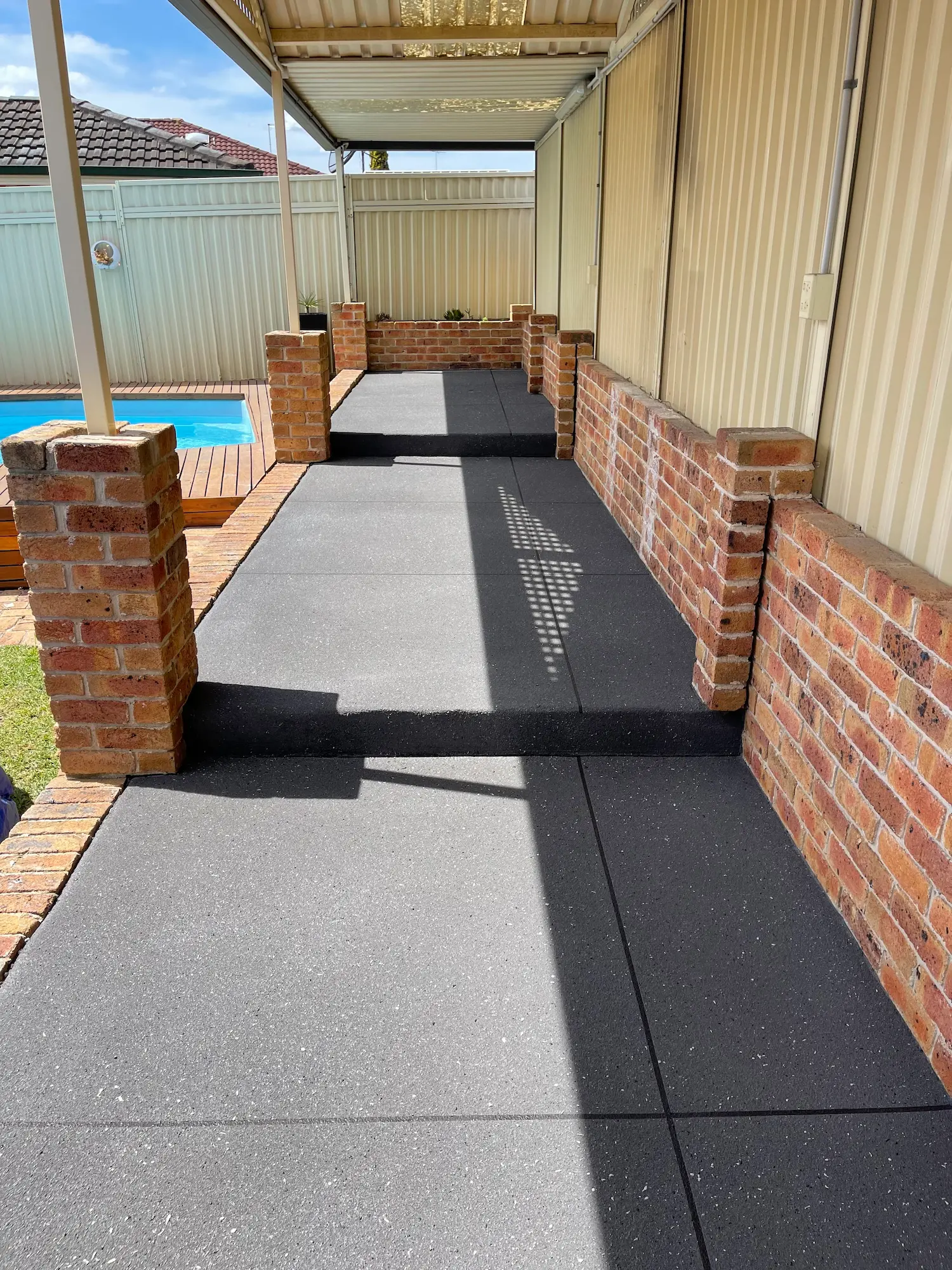 Spray-crete pathway beside a pool and brick columns