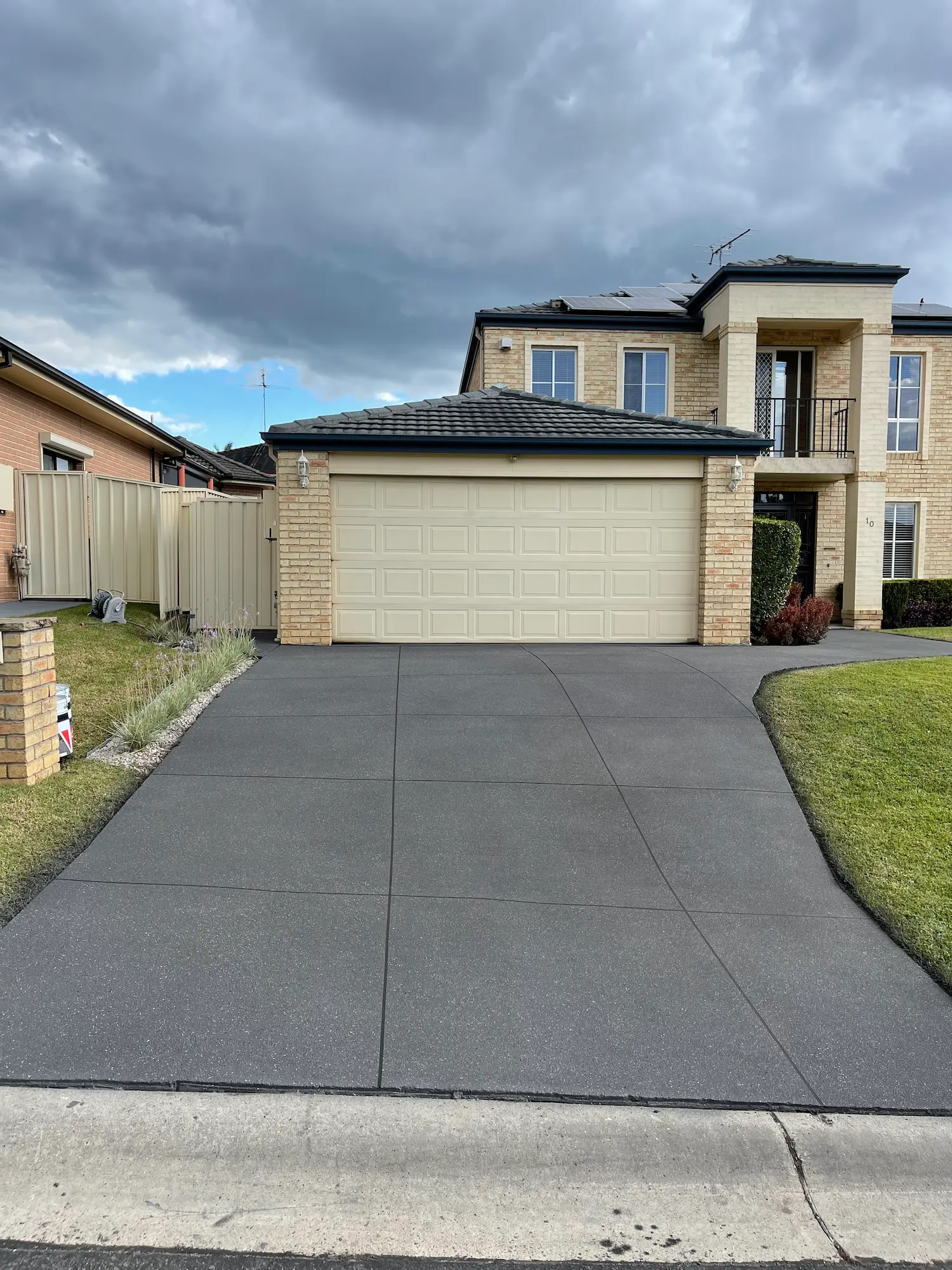 Charcoal spray-crete driveway on a two-storey home