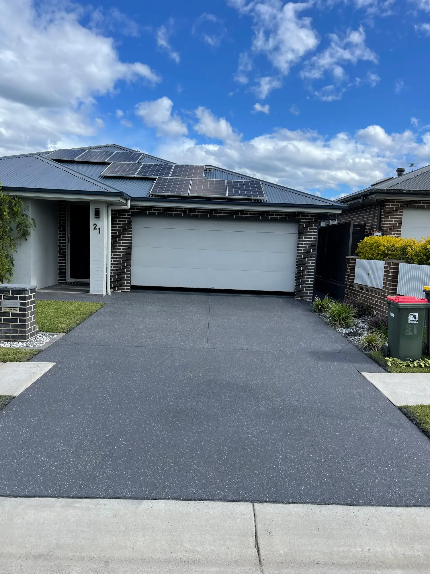 Dark grey spray-crete driveway on a new single-storey home