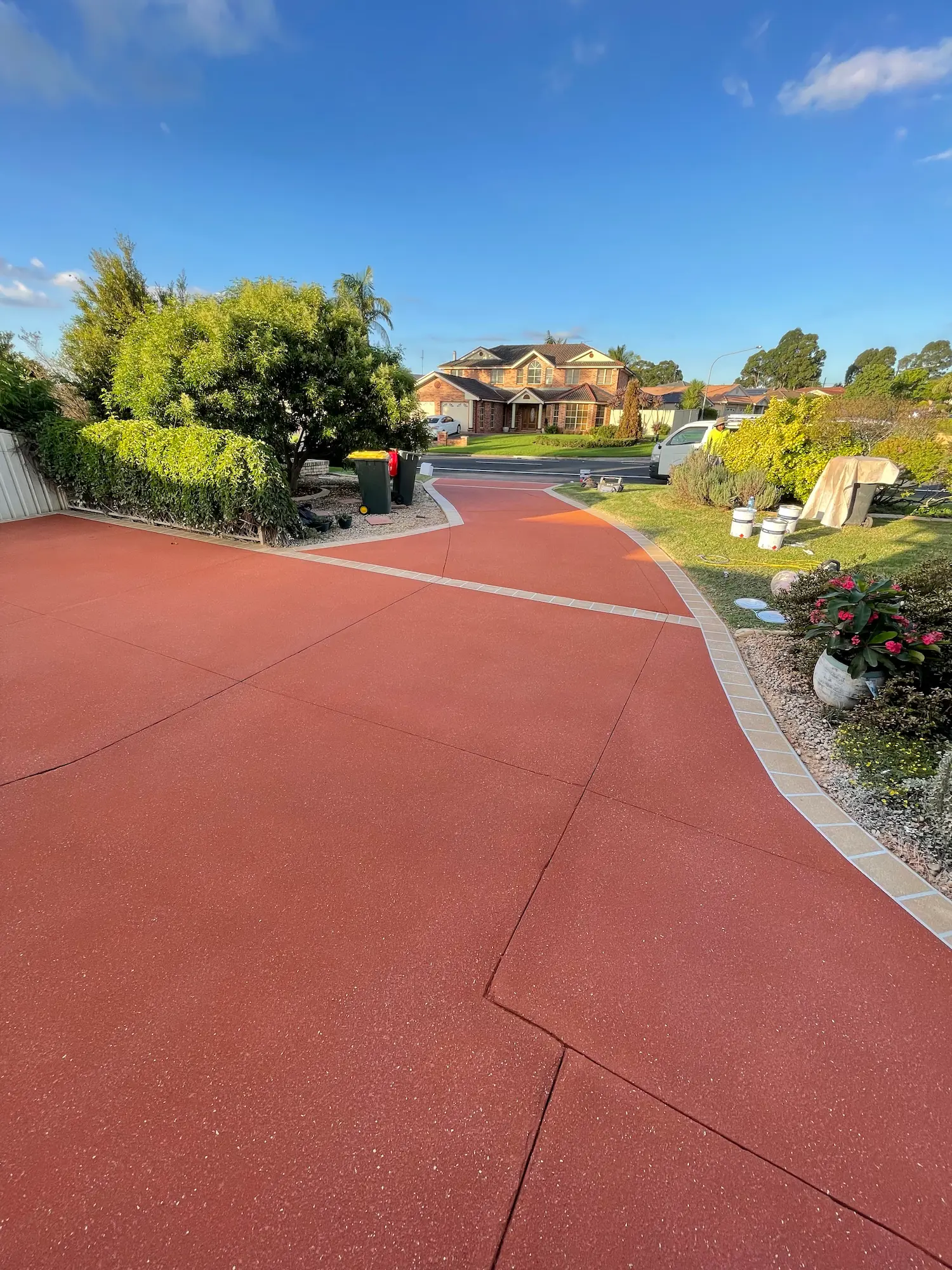 Long red spray-crete driveway with border
