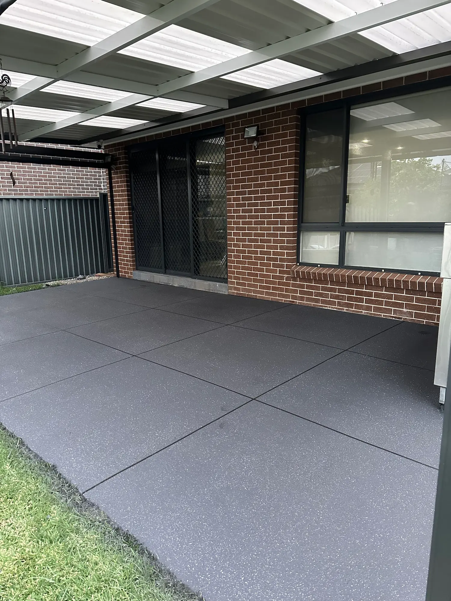 Charcoal spray-crete alfresco area beside a brick home