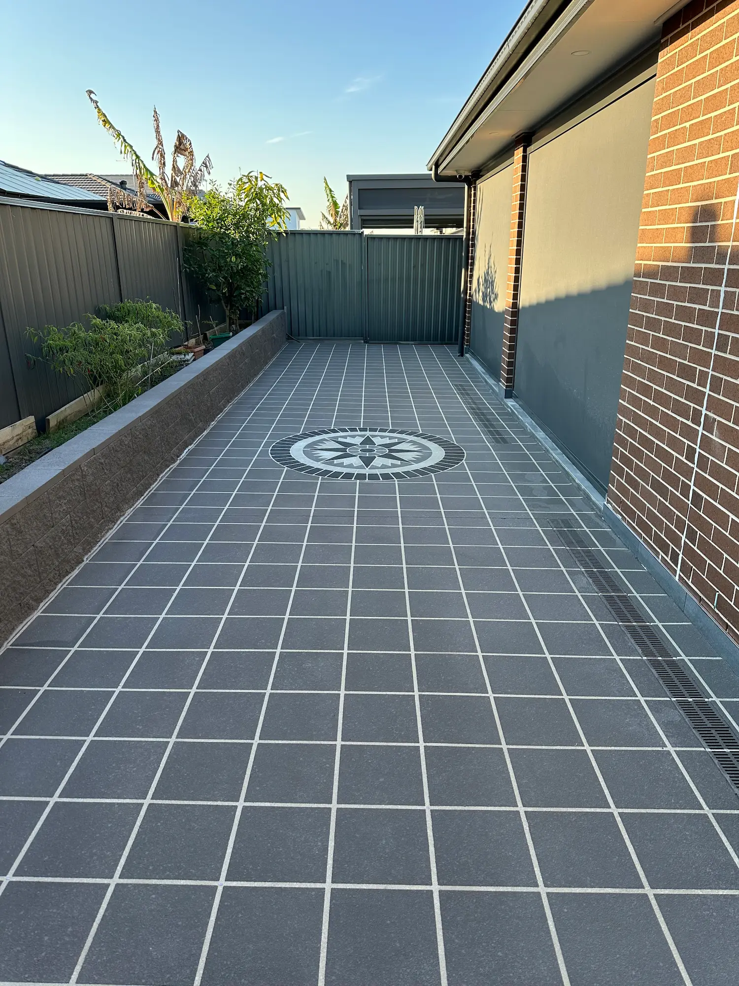 Grey tile-pattern spray-crete side path with compass feature